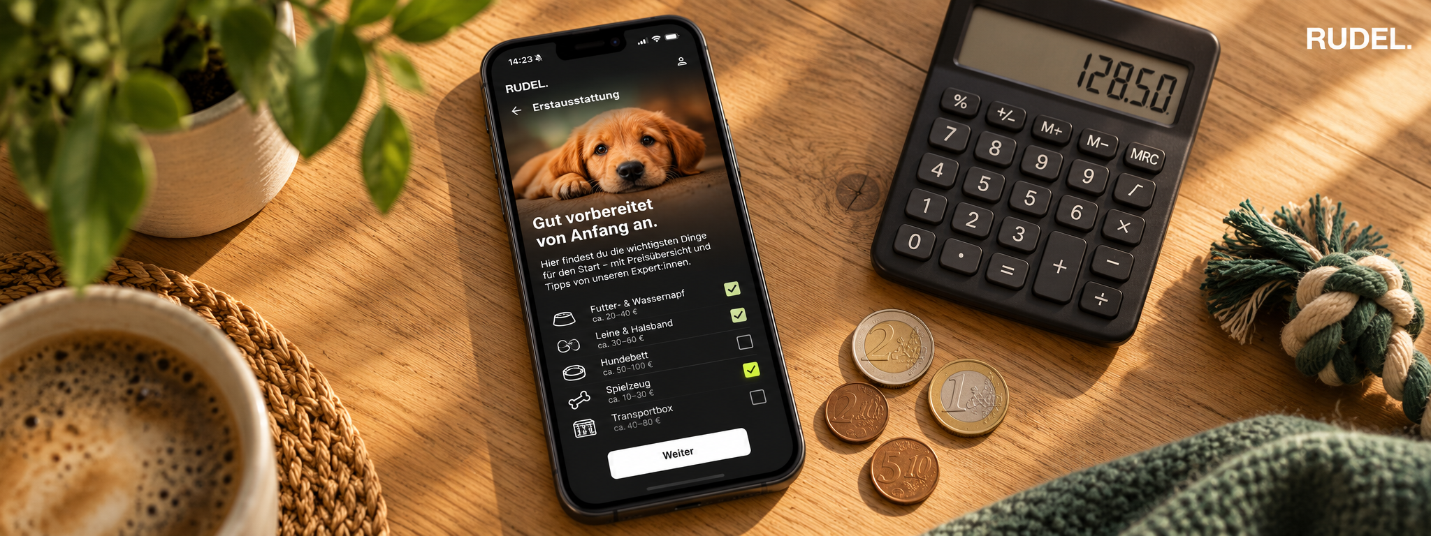 Ein Smartphone mit der RUDEL App liegt neben einem Taschenrechner mit der Anzeige 128,50 und ein paar Münzen auf einem Holztisch, während im Hintergrund eine Tasse Kaffee steht